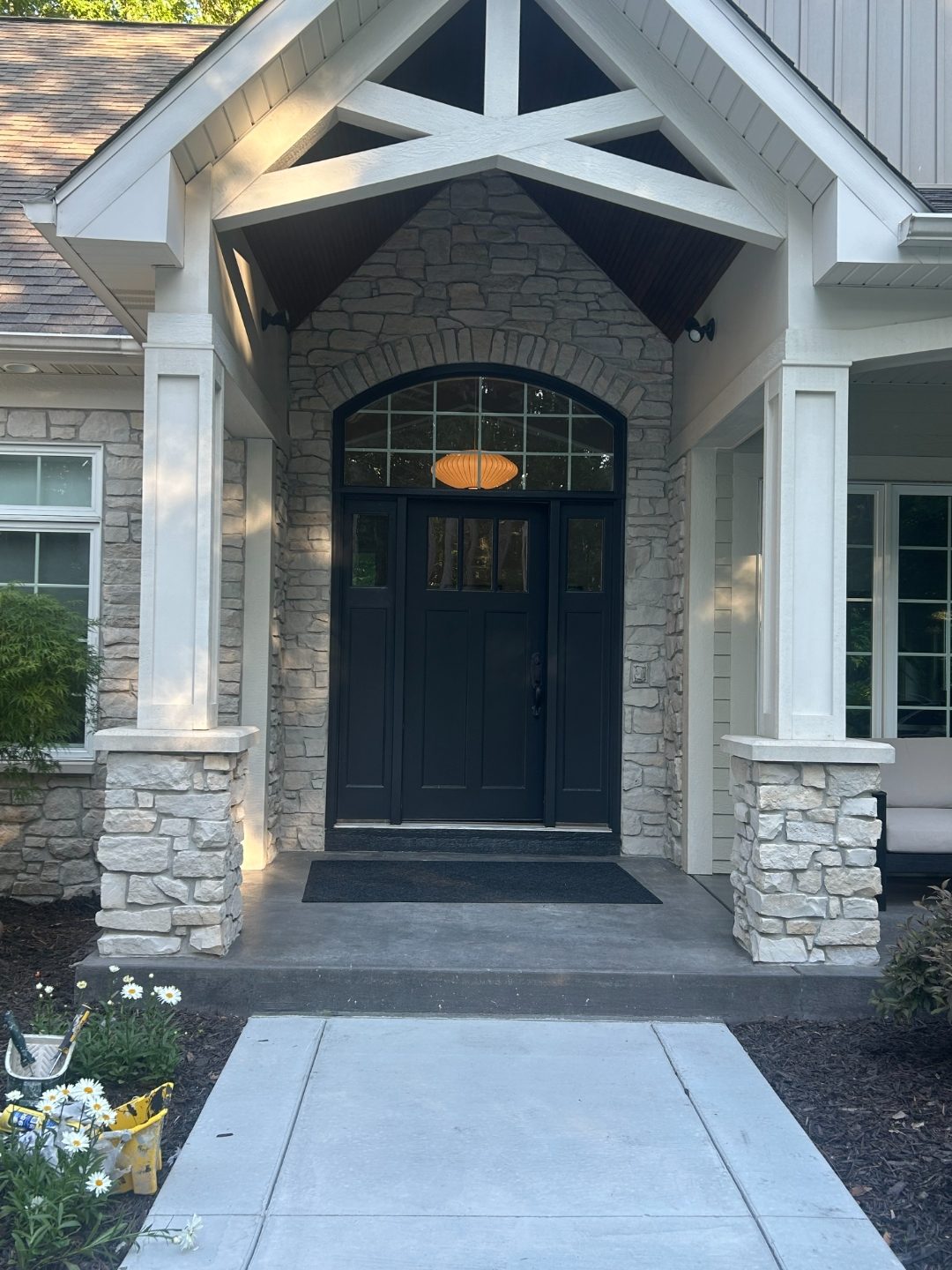 Custom stone entry with painted black arched door by GRC Painting